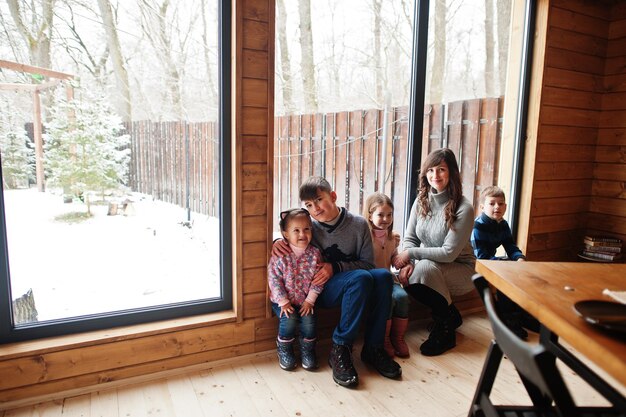 Mãe e filhos em casa de madeira moderna com mesa passando tempo juntos em calor e amor