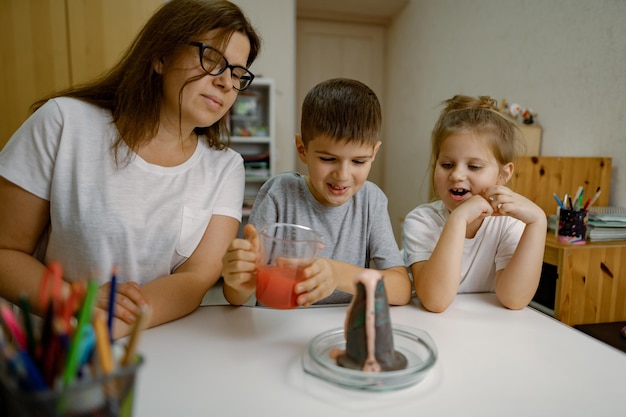 Mãe e filhos em casa estão realizando um experimento com erupção vulcânica