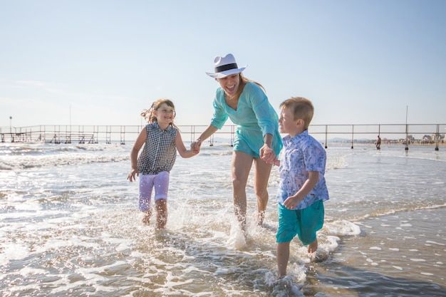 Mãe e filhos estão brincando no mar na praia