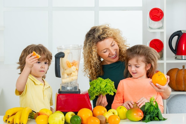 Mãe e filhos estão preparando os legumes e frutas, feliz e amorosa família saudável, smoothie spin