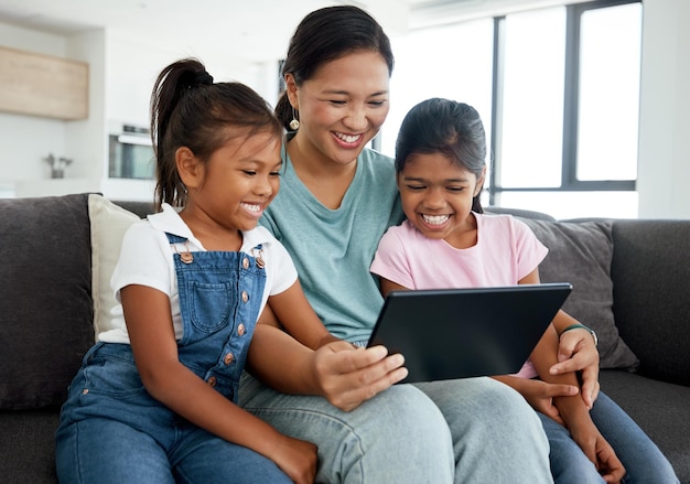 Mãe e filhos felizes com tablet digital assistem a vídeos engraçados,  filmes ou jogos no sofá