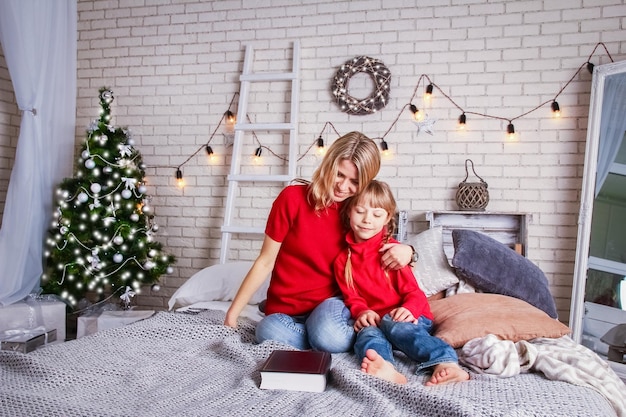 Mãe e filhos felizes lendo um livro em casa no Natal