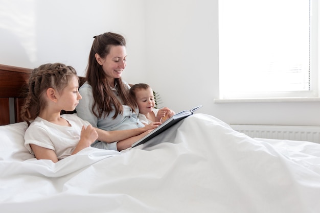 Mãe e filhos lendo um livro na cama no luto