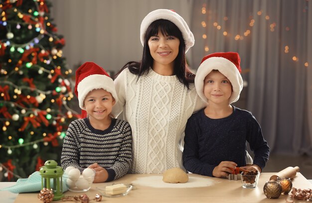 Mãe e filhos pequenos fazendo biscoitos de Natal na cozinha