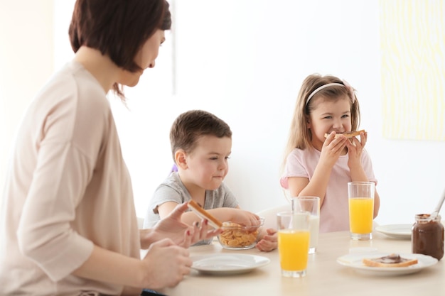 Mãe e filhos tomando café da manhã em casa