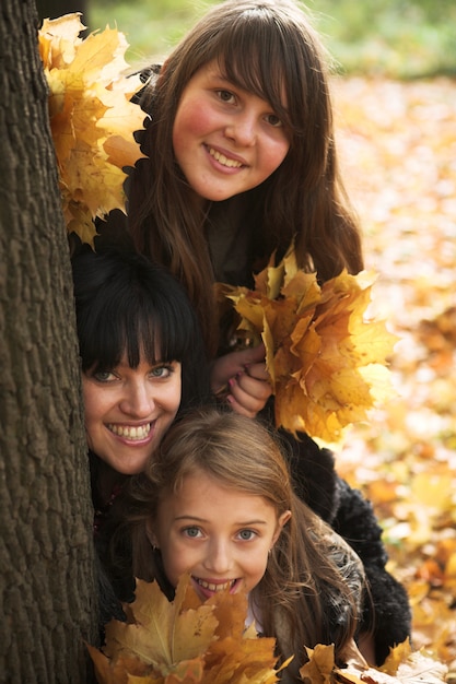 mãe e irmãs atrás de uma árvore