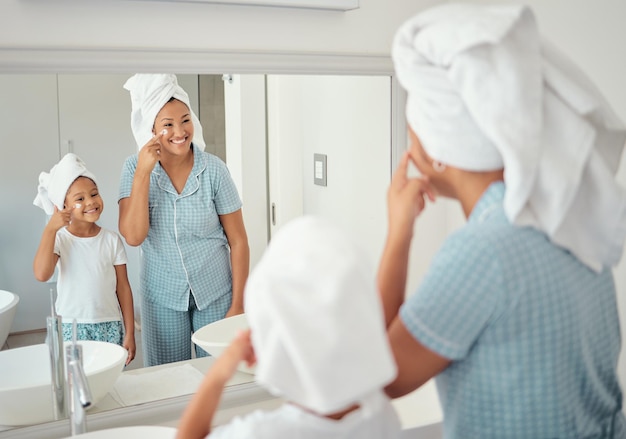 Mãe e menina fazendo cuidados com a pele de manhã no banheiro juntos Família negra em sua casa fazendo rotina de cuidados com a pele usando produtos e loção no rosto Creme de rosto familiar e cuidados faciais