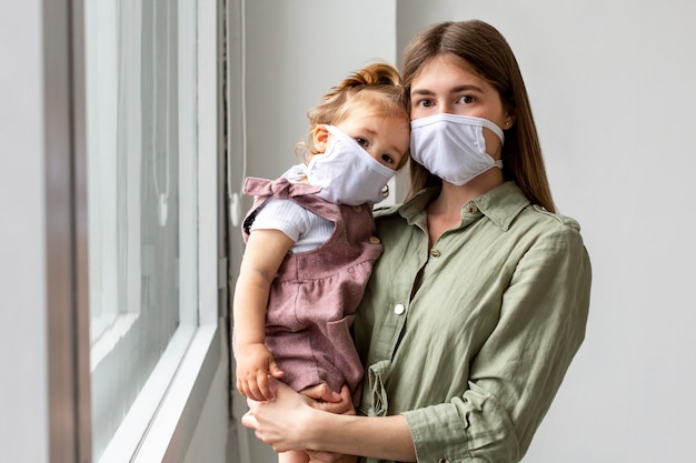 Foto mãe e menina vestindo máscaras médicas