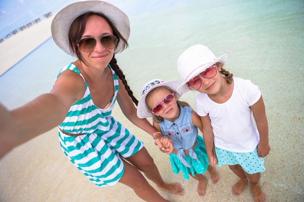 Mãe e meninas tomando selfie na praia tropical