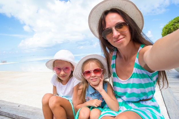 Mãe e meninas tomando selfie na praia tropical