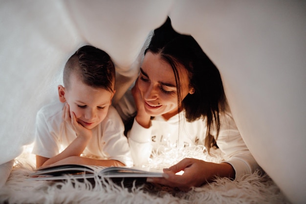 Mãe e mulher a ler um livro na cama.