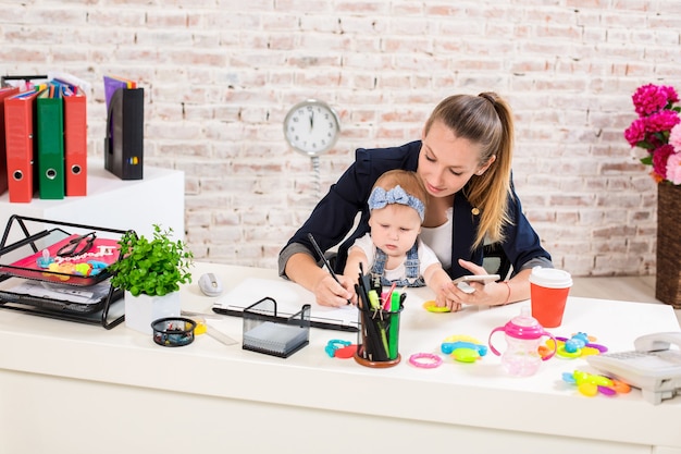 Mãe e mulher de negócios trabalhando com laptop em casa e brincando com sua filha.