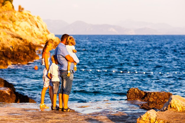 mãe e pai com filhos andam na praia por do sol, férias em família