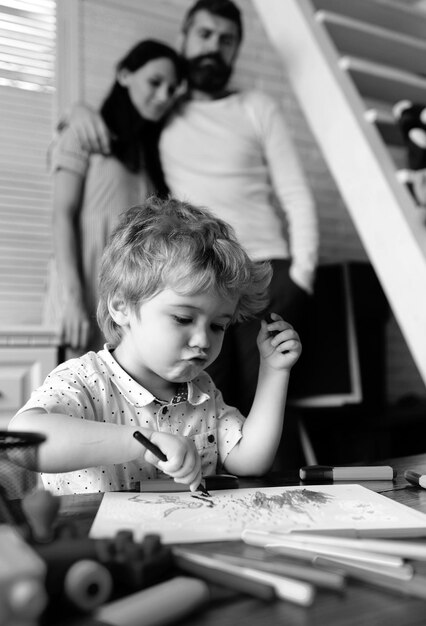 Mãe e pai desenhando com a criança família feliz de três se divertindo juntos pais alegres brincando