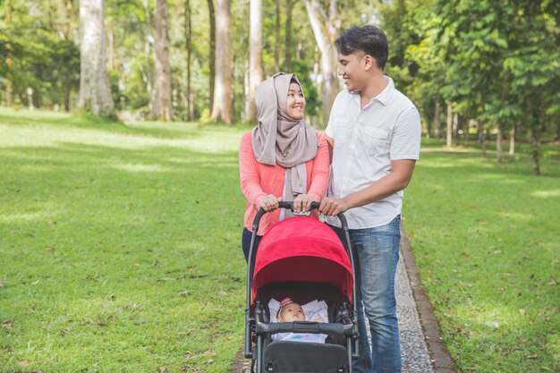 Mãe e pai empurrando carrinho de bebê no parque