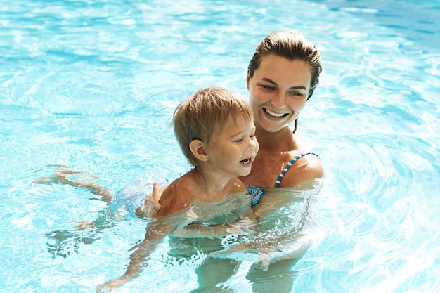 Mãe e seu filho bonitinho nadando na piscina ao ar livre durante as férias de verão