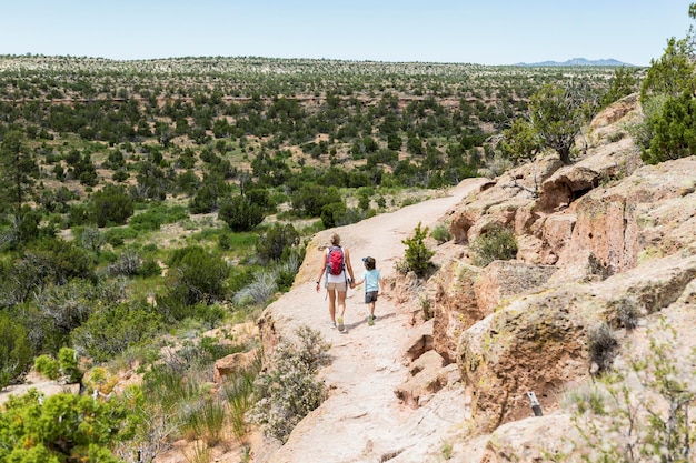 mãe e seu filho de 5 anos andando pelo caminho, ruínas de Tsankawi, NM