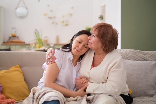 Mãe e sua filha adulta apreciando momentos preciosos conversando e rindo em um sofá confortável fortalecendo os laços familiares através de experiências e conversas compartilhadas