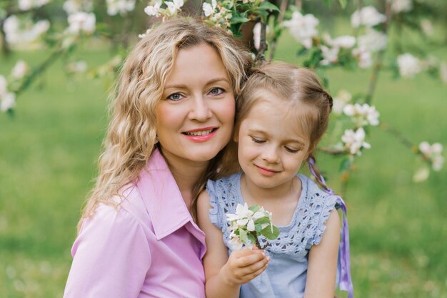 Mãe e sua filha se divertem na primavera em um parque florido