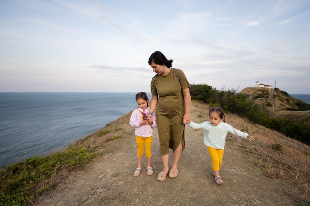 Mãe e suas duas filhas caminhando por um caminho de montanha ao lado do mar