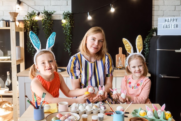 Foto mãe e suas duas filhas mostrando ovos de páscoa devidos conceito de preparação de férias de páscoa