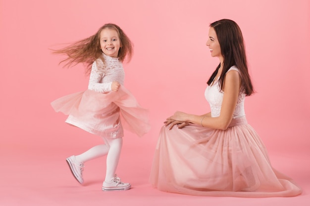 Foto mãe encantadora e filha sorridente em fundo rosa