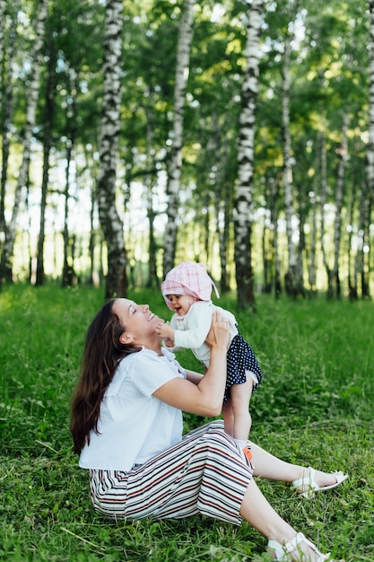 Mãe engraçada com bebê sentado na grama
