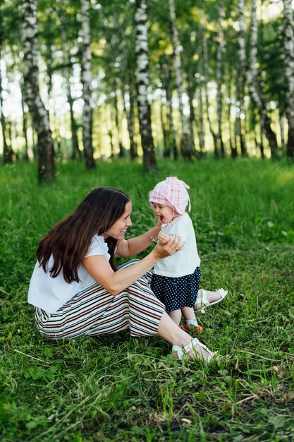 Mãe engraçada com bebê sentado na grama