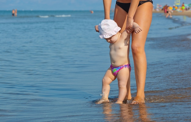 Mãe ensina a filha a caminhar até a praia.