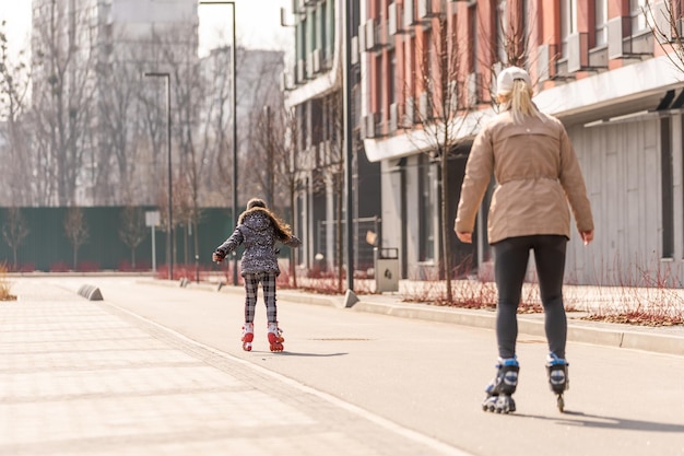 Foto mãe ensina filha a andar de patins.