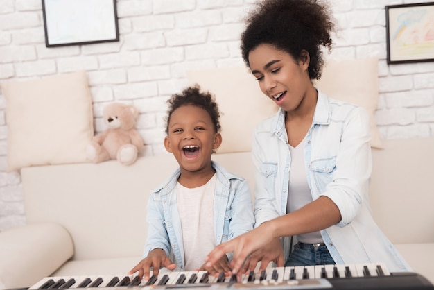Mãe ensina uma menina a tocar piano.