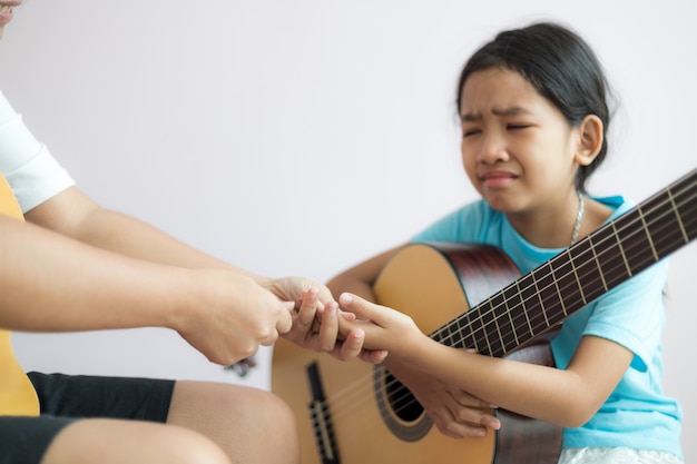 Mãe ensinando a filha a aprender a tocar violão clássico