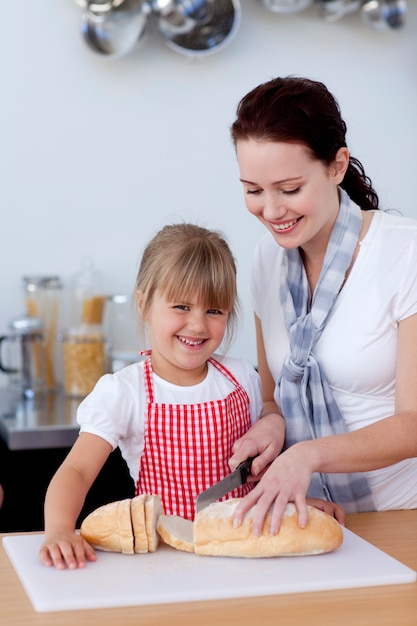 Mãe ensinando a filha como cortar pão