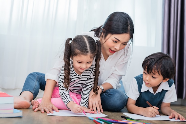 Mãe ensinando crianças na aula de desenho. Filha e filho pintando com cor de creiom