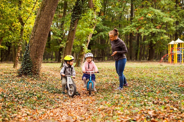 Mãe ensinando e apoiando seus filhos no passeio de bicicleta