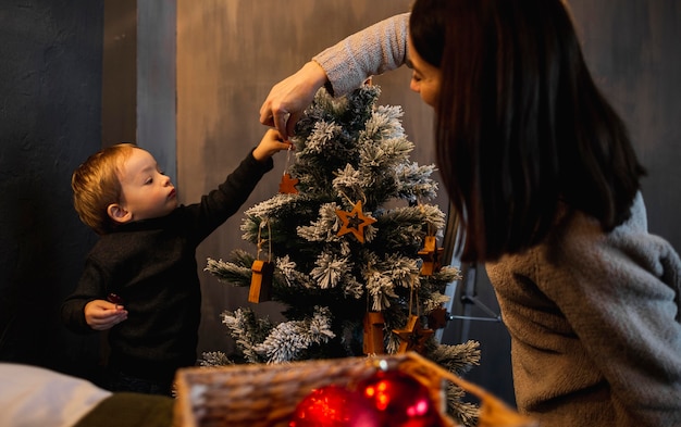 Foto mãe ensinando filho a decorar árvore de natal