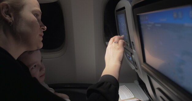 Mãe ensinando filho a usar monitor de assento no avião