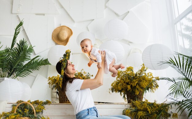 Mãe está brincando com sua filha bebê em um fundo festivo de primavera. Buquês de mimosa