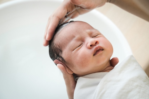 Mãe está lavando o cabelo do bebê. Mãe, limpando o cabelo do bebê.