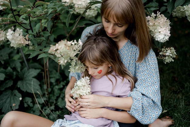 Mãe está segurando sua filha pequena do lado de fora na natureza da primavera.