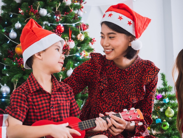 Mãe estava tocando violão no dia de natal com menino, família comemorando o natal em casa