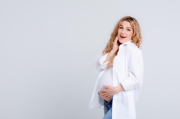 Mãe expectante toca seu estômago em um fundo branco Foto de estúdio