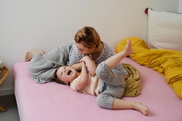 Mãe fazendo cócegas na cama brincando de manhã