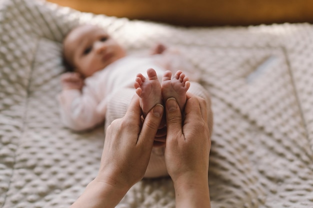 Mãe fazendo massagem de bebê mãe massageando bebê pé nu massagem preventiva para recém-nascido