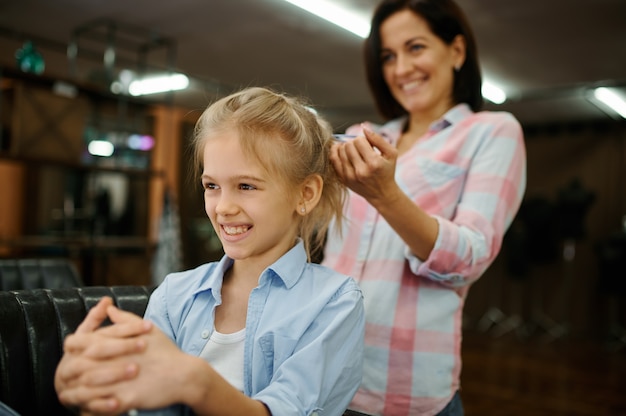 Mãe fazendo o penteado da filha no salão