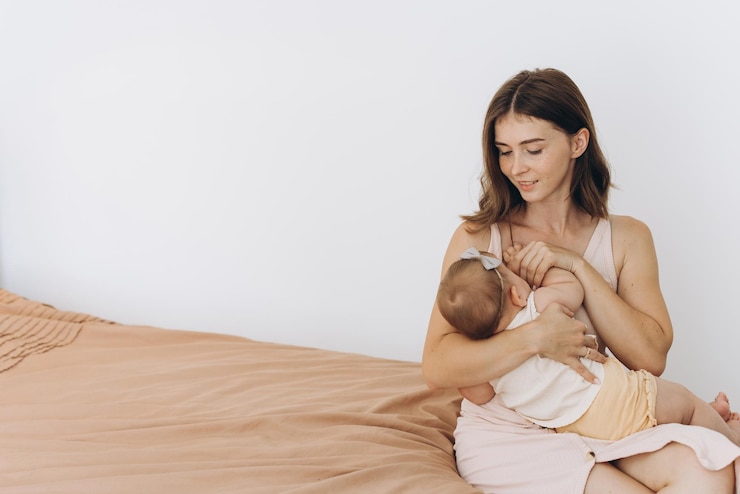 Mãe feliz amamentando uma menina em uma cama em uma sala brilhante