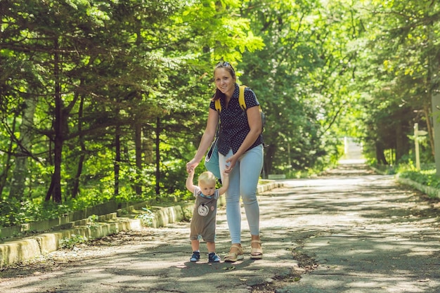 Mãe feliz brincando com o bebê no parque no outono. Criança sorrindo para a mãe com as mãos no parque no outono