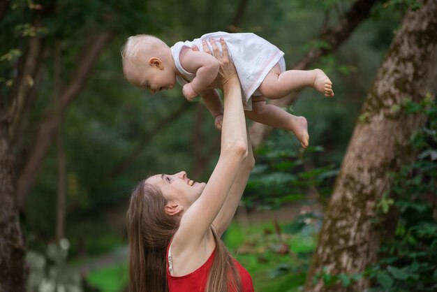 Mãe feliz brincando com seu bebê ao ar livre. Conceito de União com criança.