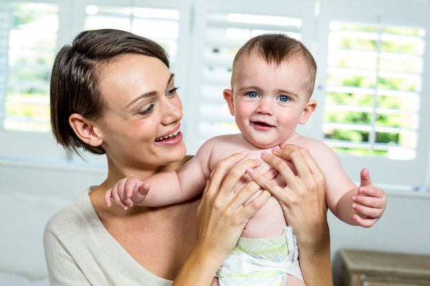 Mãe feliz, carregando o filho em casa