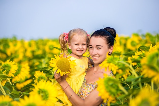 Foto mãe feliz com a filha no campo com girassóis